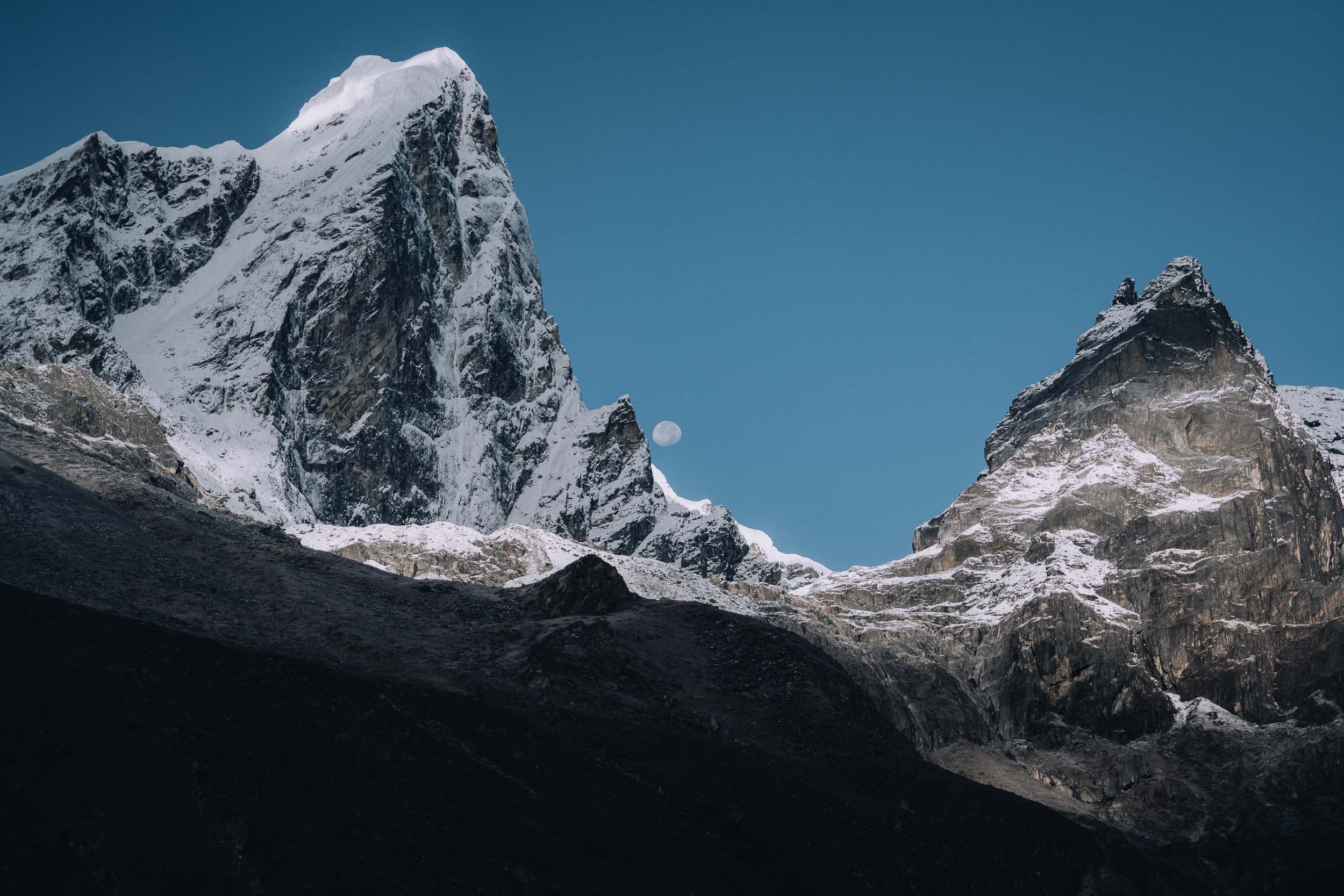 the moon rising over the mountains